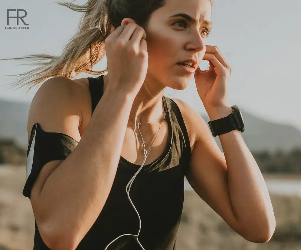 A female runner running while listening to her favorite music on her phone which is placed inside the armband wrapped around her upper arm