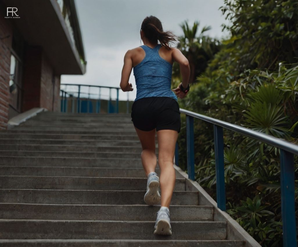 an image of an female runner running on the stairs while wearing running t-shirt, shoes & short running shorts